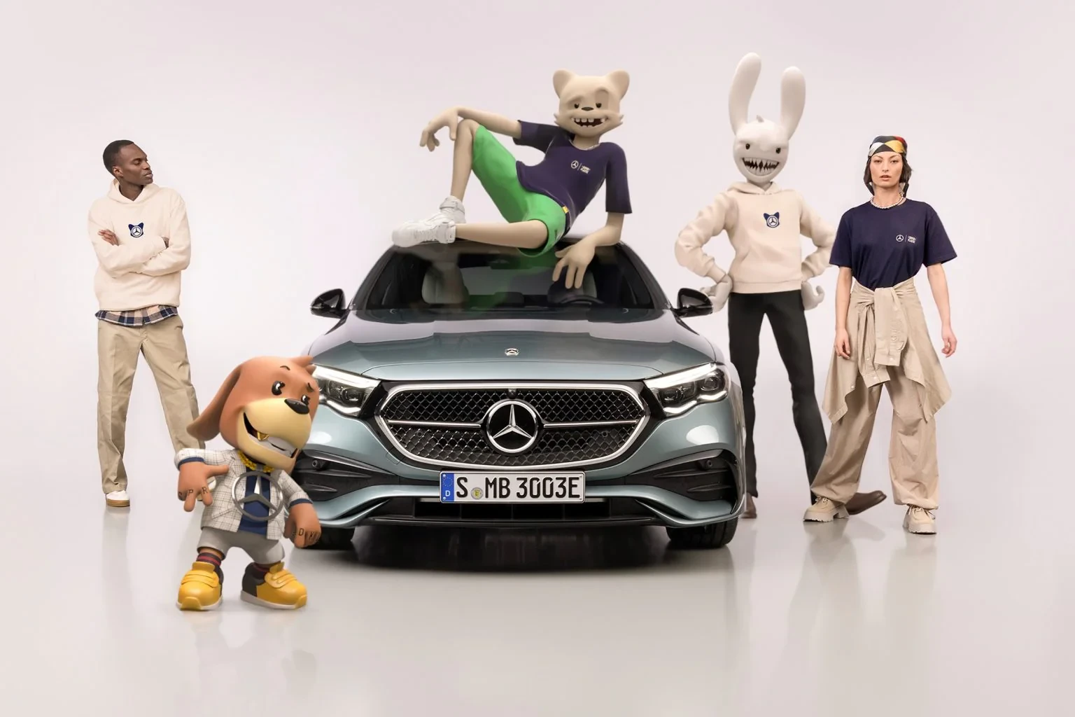 Janky and Guggimon posed with models around a Mercedes vehicle.
